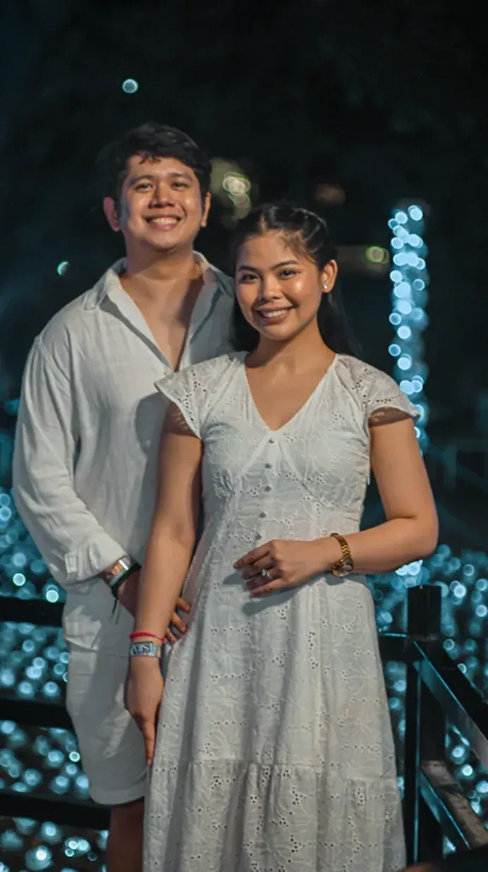 Tommy and Jeyan standing together among soft festival lights