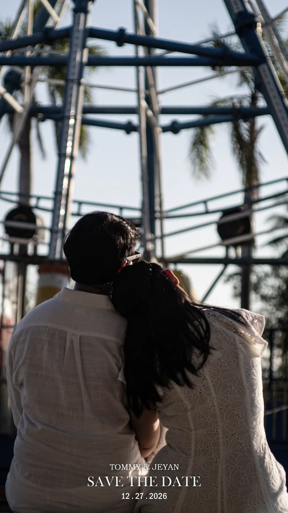 Tommy and Jeyan sitting close, looking up at a fairground ride